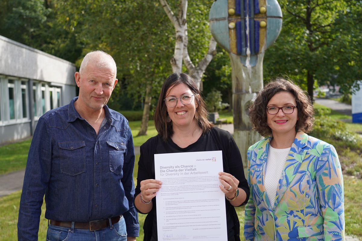 Prof. Dr. Olf Köller, Dr. Marta Chiarinotti und Mareike Bierlich stehen vor dem IPN-Gebäude und halten die Charta der Vielfalt in der Hand.