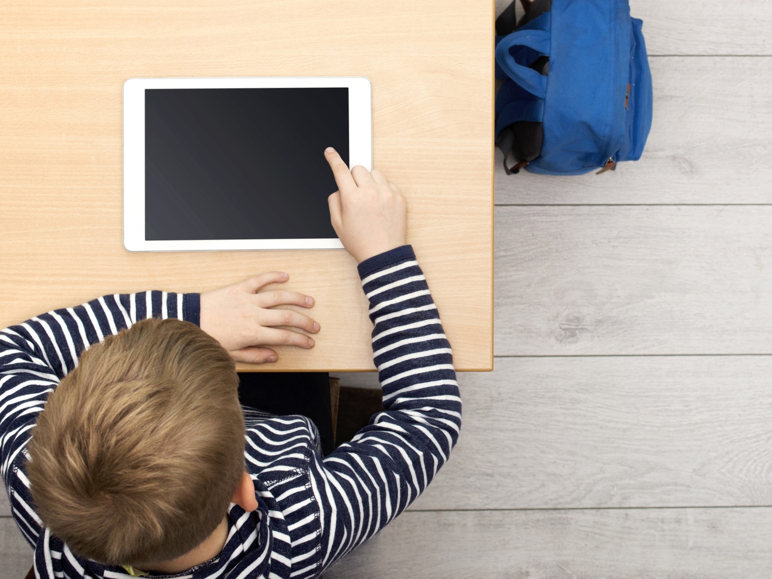 Ansicht von oben auf einen Schüler, der ein Tablet benutzt.